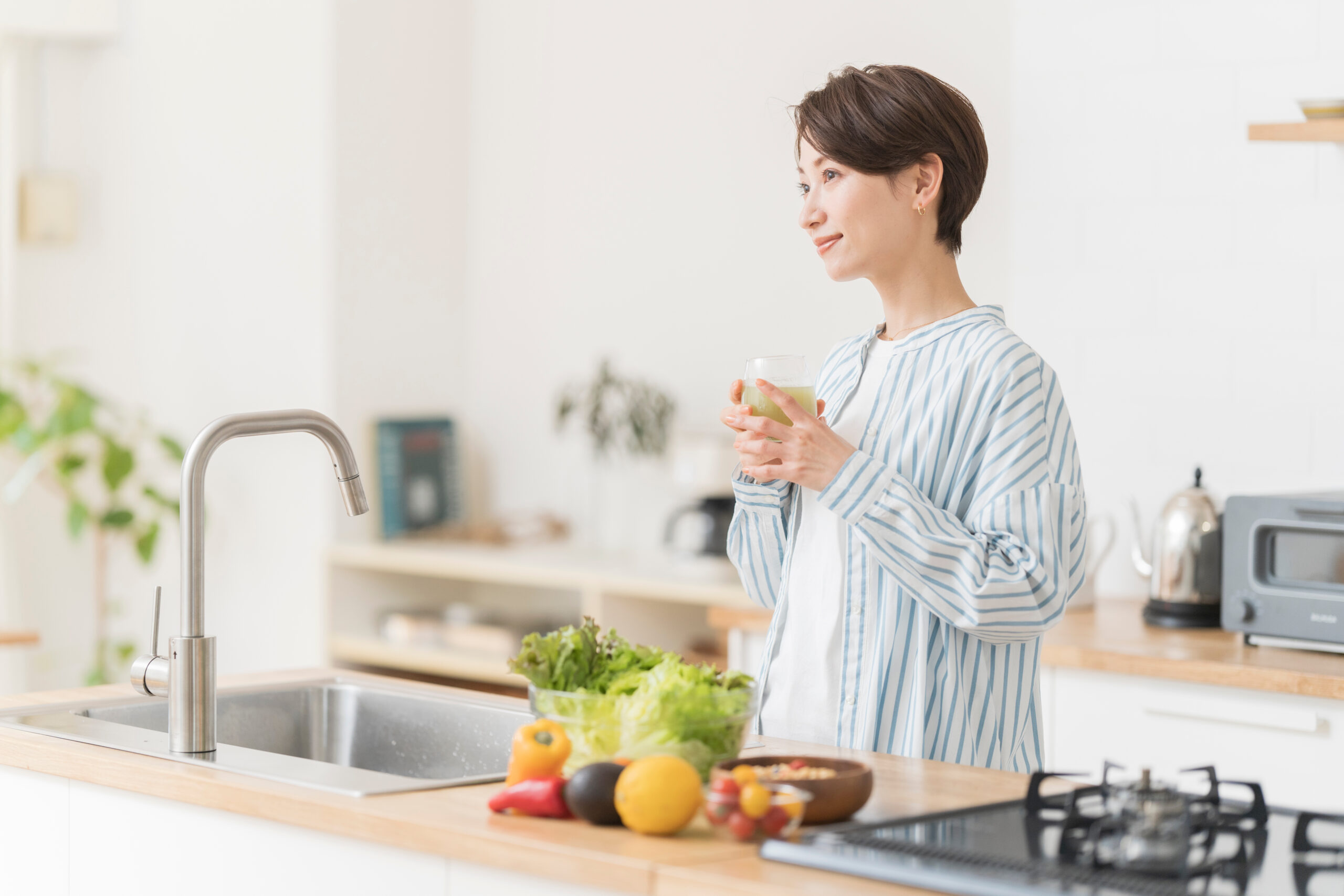 キッチンで青汁を持つ女性の写真