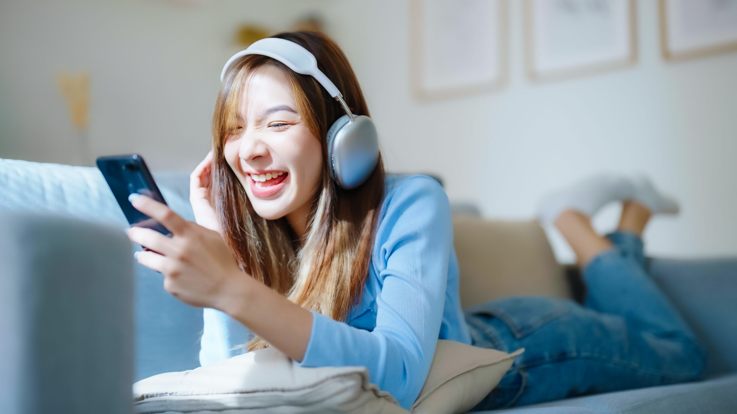 ヘッドホンで音楽を聴きながらスマホを見て笑っている女性